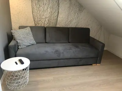 a black couch in a living room with a table at Apartamenty Premium Wadowice in Wadowice