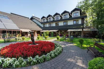 a statue in a flower bed in front of a building at Hotel Badura in Wadowice