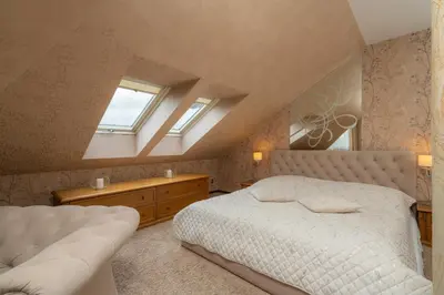 a bedroom with a large bed and two windows at Hotel Badura in Wadowice
