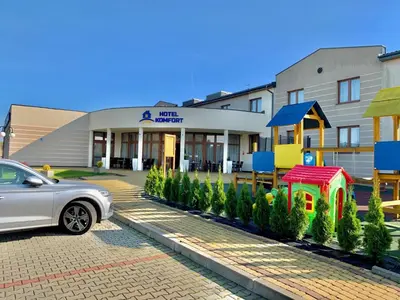 a white car parked in front of a building at Hotel Komfort in Krzywaczka