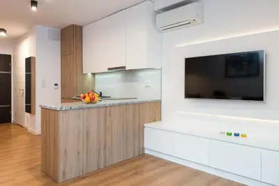 a kitchen with white cabinets and a flat screen tv at Old Town, Kazimierz, large luxurious, 2 bedroom 2 bathroom, Airco in Kraków
