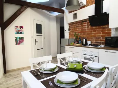 a kitchen with a dining table with white appliances at Apartament krakowski GIMO na Kazimierzu in Kraków