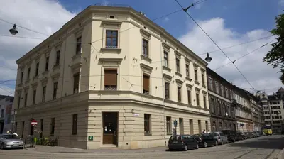 a large white building with cars parked in front of it at Apartament krakowski GIMO na Kazimierzu in Kraków