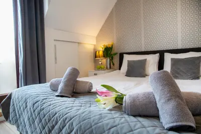 a bedroom with a bed with towels and flowers on it at LUXURIOUS APARTMENTS Cracow in Kraków