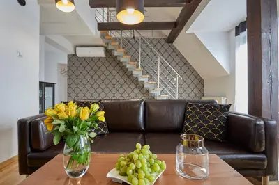a leather couch with a table with a vase of yellow flowers at LUXURIOUS APARTMENTS Cracow in Kraków