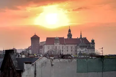 a building with a sunset in the background at LUXURIOUS APARTMENTS Cracow in Kraków