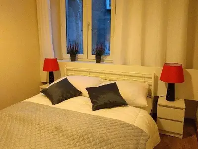 a bedroom with a bed with two lamps and a window at OldKrak Apartment in Kraków