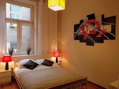 a bedroom with a bed with two lamps and a window at OldKrak Apartment in Kraków