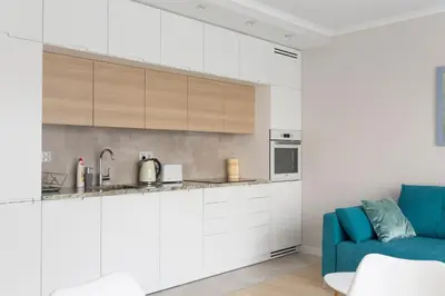 a kitchen with white cabinets and a blue couch at Chopin Apartments in Kraków
