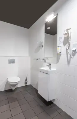 a white bathroom with a toilet and a sink at Great Polonia Kraków City Center in Kraków