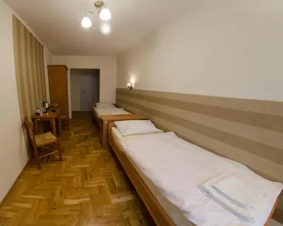 a row of beds in a room with wooden floors at Brama Old City Rooms in Kraków