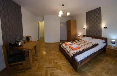a bedroom with a large bed and a wooden table at Brama Old City Rooms in Kraków