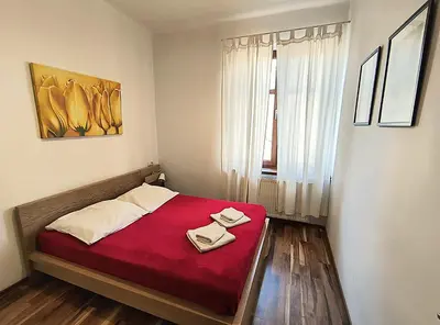 a bedroom with a red bed with two towels on it at Apartament Premium in Kraków