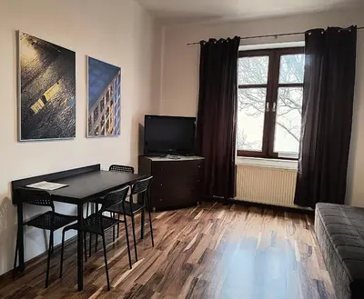 a living room with a table and chairs and a television at Apartament Premium in Kraków