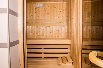 a wooden sauna with a bench in the middle at Sauna Luxurious Apartment in Kraków