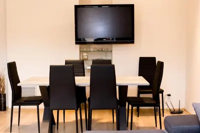a dining room with a table and chairs with a tv on the wall at Sauna Luxurious Apartment in Kraków