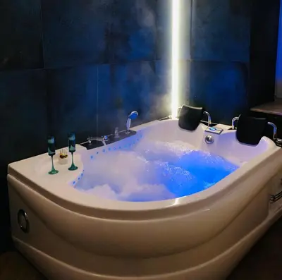 a bath tub with a bottle of wine and two wine glasses at Jacuzzi & Bike Apartment, Krakow in Kraków