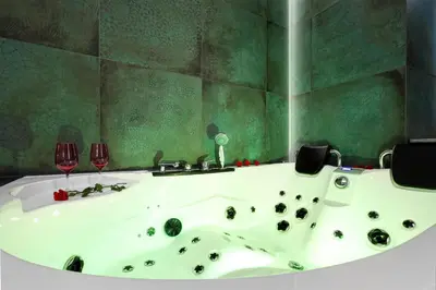 a bathroom with a bath tub and two wine glasses at Jacuzzi & Bike Apartment, Krakow in Kraków