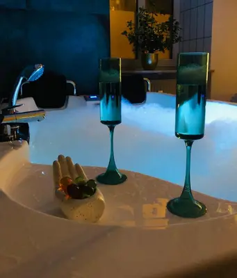 two glasses of water and a plate of food in a tub at Jacuzzi & Bike Apartment, Krakow in Kraków