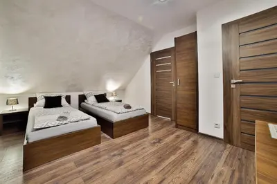 two beds in a room with wooden floors at Noclegi u Nawary in Rabka