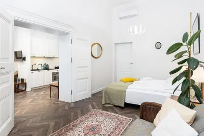 a white bedroom with a bed and a kitchen at Otium Old Town Sarego in Kraków