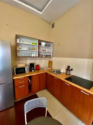 a kitchen with wooden cabinets and a stainless steel refrigerator at Ametyst Hostel in Kraków