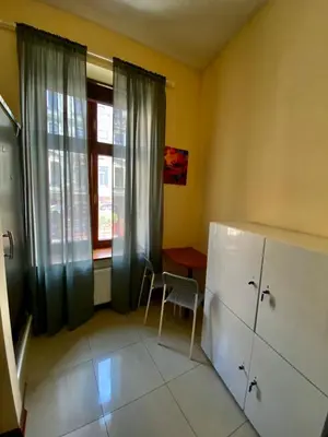 a kitchen with a refrigerator and a table and a window at Ametyst Hostel in Kraków