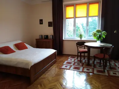 a bedroom with a bed and a table and a window at Studio Krakowski Styl in Kraków