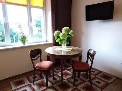 a table with chairs and a vase of flowers on it at Studio Krakowski Styl in Kraków