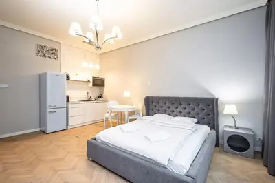 a bedroom with a large bed and a kitchen at RentPlanet - Studio Krasińskiego in Kraków