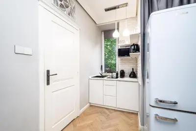 a kitchen with white cabinets and a white refrigerator at RentPlanet - Studio Krasińskiego in Kraków