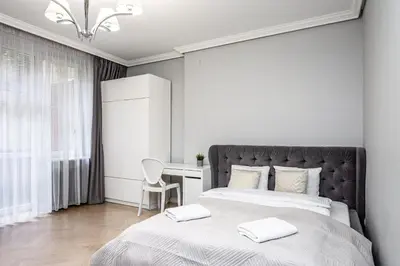 a white bedroom with a bed and a desk at RentPlanet - Studio Krasińskiego in Kraków