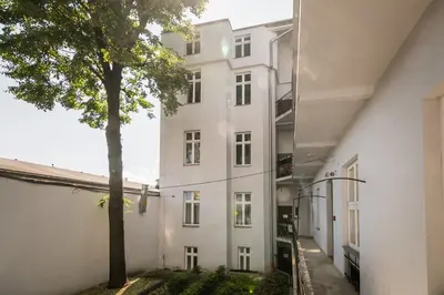 a white building with a tree in front of it at Royal City Apartments Old Town in Kraków