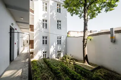 a tree in front of a white building at Royal City Apartments Old Town in Kraków