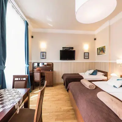 a hotel room with two beds and a table and chairs at Apartamenty Kajzer in Kraków