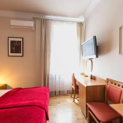 a bedroom with a red bed and a desk and a window at Apartamenty Kajzer in Kraków