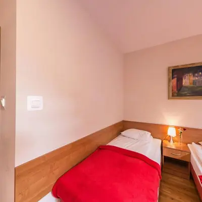a bedroom with two beds with a red blanket at Apartamenty Kajzer in Kraków