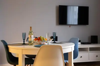 a dining room table with a bottle of wine and chairs at Grey Apartments Kościuszko in Kraków