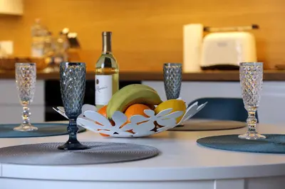 a table with a bowl of fruit and a bottle of wine at Grey Apartments Kościuszko in Kraków