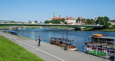 a person riding a skateboard down a road next to a river at Grey Apartments Kościuszko in Kraków