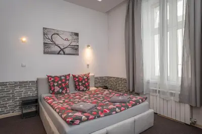 a bedroom with a bed with red pillows and a window at 70s Hostel in Kraków