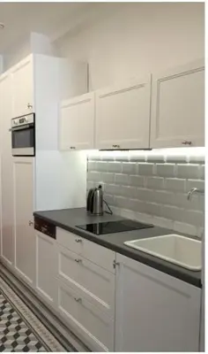 a white kitchen with a sink and white cabinets at Florianska Deluxe Apartments with Air Condition in Kraków