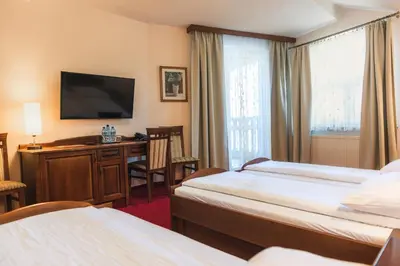 a hotel room with two beds and a flat screen tv at Dworek Skawiński in Skawina