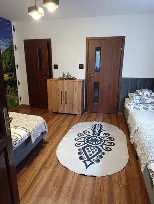 two beds in a room with wooden floors and a window at Czesławka in Zawoja