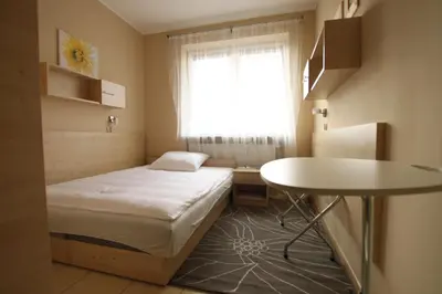 a small room with a bed and a table and a window at Standard Delegacyjny Bed & Breakfast in Dąbrowa Górnicza