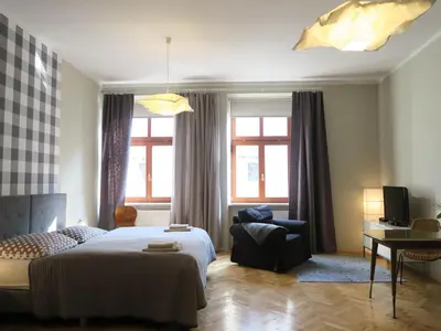a bedroom with a bed and a chair and windows at Pokoje Gościnne Poselska 20 in Kraków