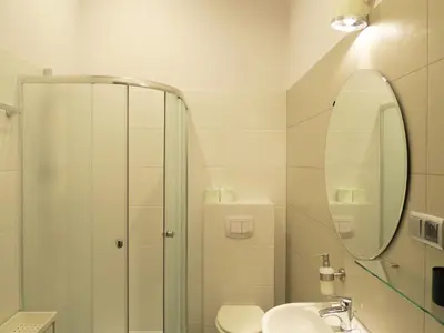 a bathroom with a shower and a sink and a mirror at Pokoje Gościnne Poselska 20 in Kraków