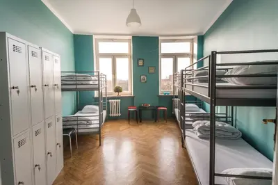 a room with three bunk beds and a table at Bubble Hostel in Kraków