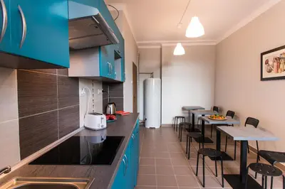 a kitchen with blue cabinets and tables and chairs at Bubble Hostel in Kraków