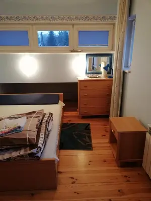 a bedroom with a bed and a dresser and two windows at Pokoje Gościnne Lalaj in Bolęcin